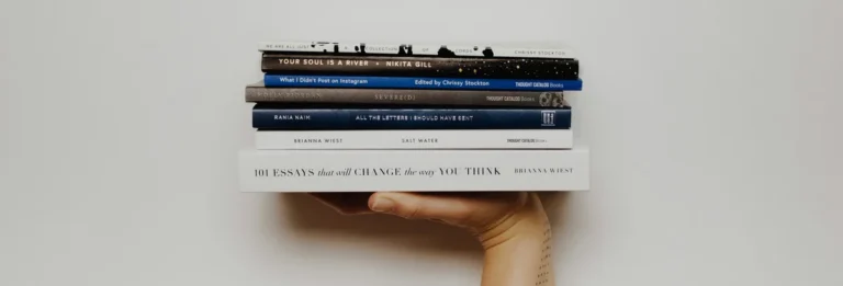 Hand holding up a stack of books