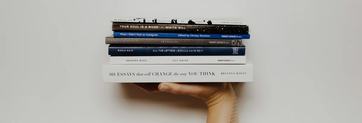 Hand holding up a stack of books